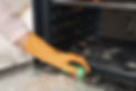 Woman cleaning oven door with sponge in kitchen, closeup_edited_edited.jpg