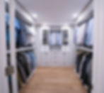 Organized walk-in closet with custom white cabinetry.
