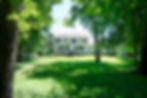 Large white house with a spacious green lawn and trees