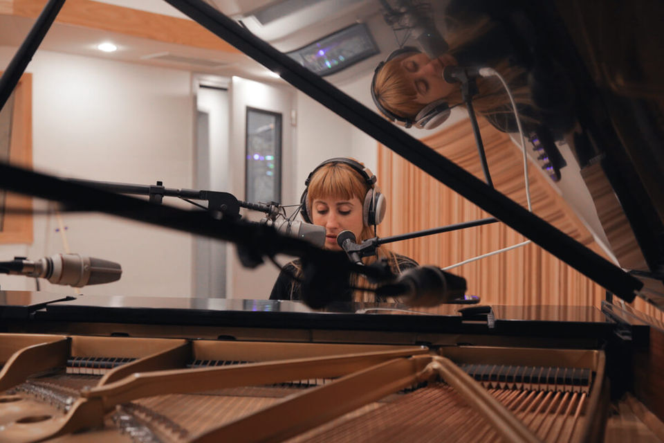 nicole miglis sitting at the steinway with several microphones around the inside of the piano and to capture her vocals. 