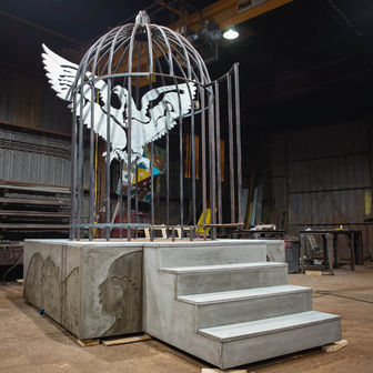 lonnie holleys sonic sculpture in progress featuring concrete stairs leading up to a metal birdcage containing a steel eagle with arduino programmed audio responses 