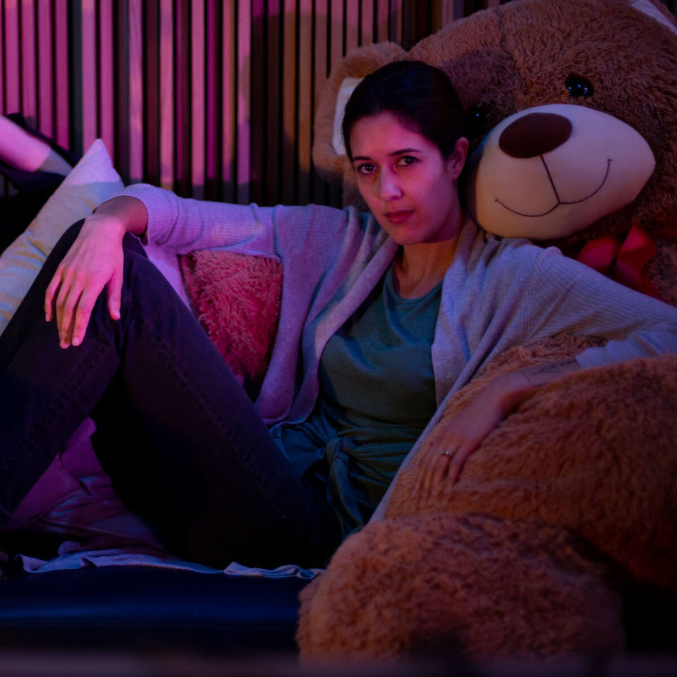 nandi rose of half waif lounging in the pulp arts control room with a giant teddy bear