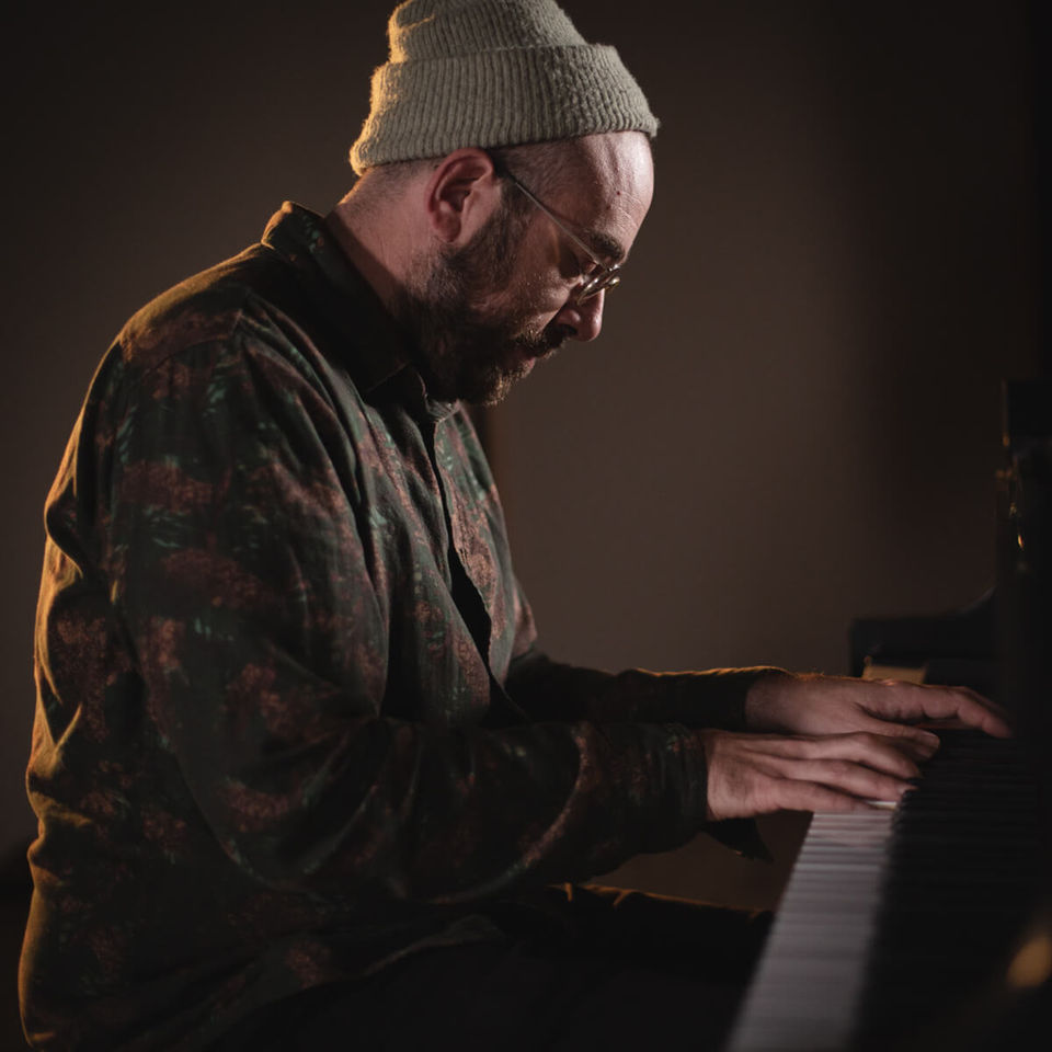 david moore also known as bing and ruth looking down and playing the steinway piano in a dark video set with dramatic lighting 
