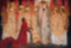 A robed figure holds a chalice amid golden-clad, angelic figures. A kneeling figure in red gazes upward. Ornate, gold vine patterns decorate.