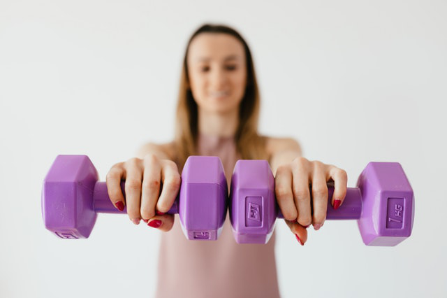 A girl holding purple dumbbells