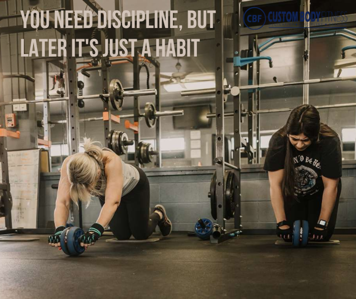 Two women do ab wheel rollouts in a gym under slogan You need discipline, but later it's just a habit and CBF Custom Body Fitness logo.