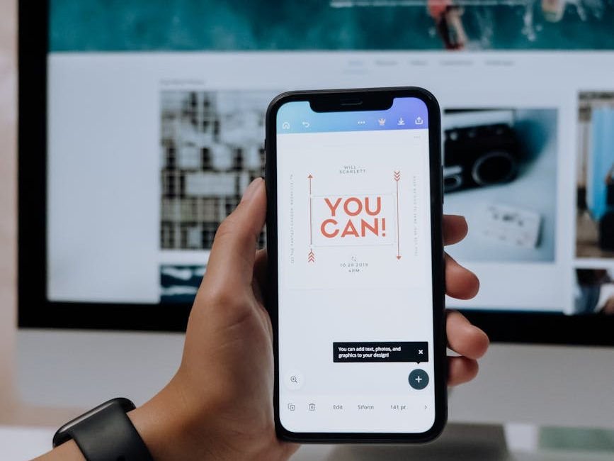 Person holding up mobile phone with the words "YOU CAN" written on in red text against a white background