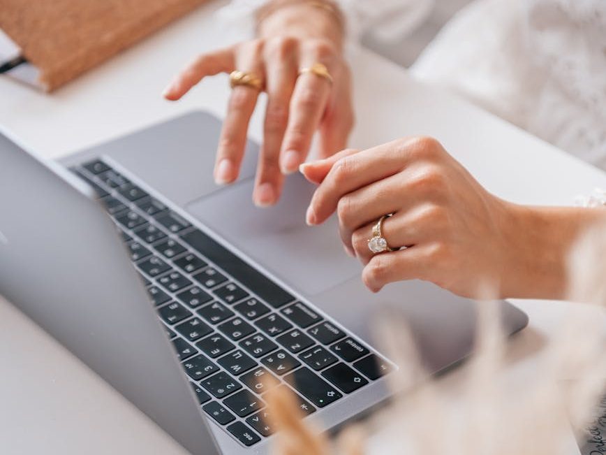 a person with rings typing on a laptop