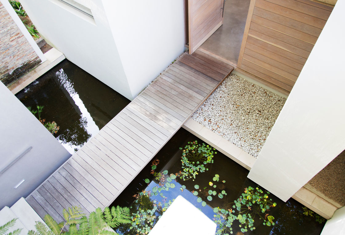 Wooden walkway over a pond with lily pads and gravel