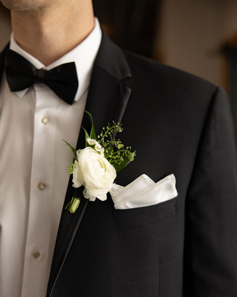 Close up of groom boutonniere with white rose on black tuxedo at White Barn at Padgett Place in Lacey Spring Alabama
