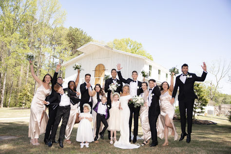 Joyful wedding party doing a ‘yay’ jump shot, all bridesmaids and groomsmen celebrating together at White Barn at Padgett Place.