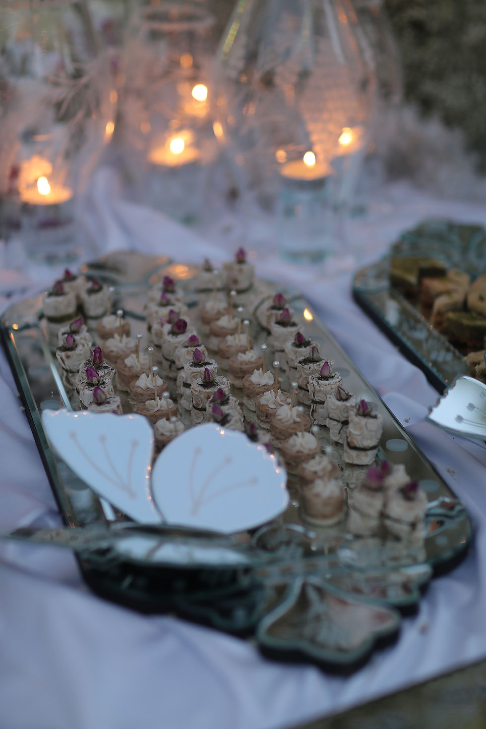 Close-up of Persian sofreh aghd sweets on a mirrored tray with a butterfly decoration at a Vancouver luxury wedding.