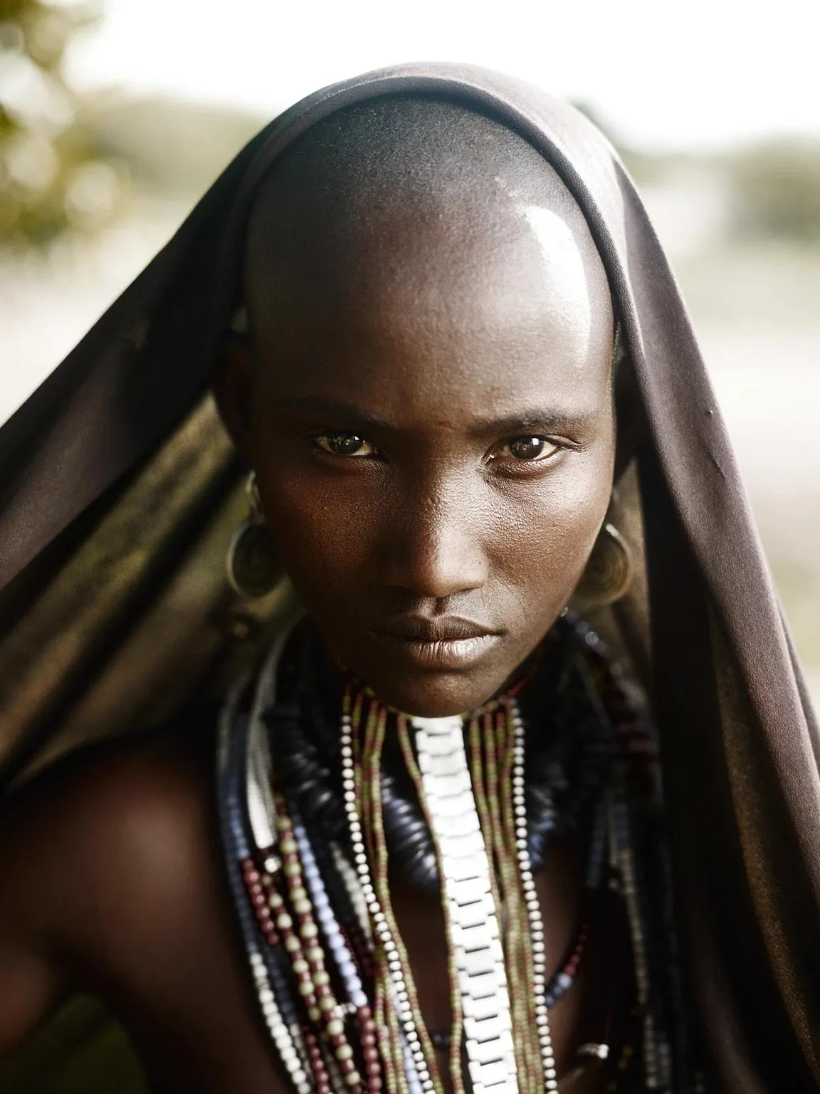 Portrait of a young Hamar woman wearing layered bead necklaces and traditional attire in the Lower O