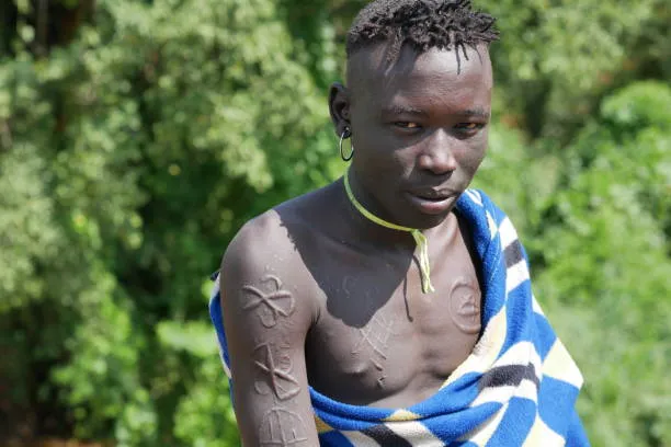 A young Suri man displays traditional scarification, a cultural expression of identity