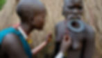 A practitioner lifts the skin with a thorn before cutting it with a razor blade, creating small wounds that will heal into raised scarification patterns.