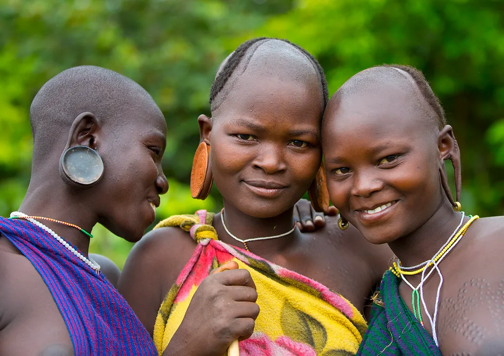 Young Suri women display distinctive stretched earlobes, beadwork, and traditional adornments