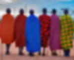 Maasai men stand together wearing brightly colored shúkàs (traditional wraps), with each distinctive pattern and color reflecting the community's enduring pastoral identity and cultural pride across East Africa.
