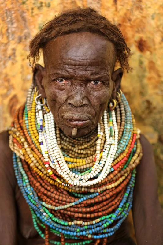 An elderly Hamar woman adorned with colorful bead necklaces,
