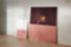 modern tv that looks like art leaning against concrete wall next to painting and herringbone patterned flooring