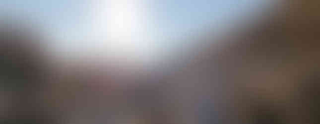 Frau blickt der Sonne entgegen an einem felsigen Weg