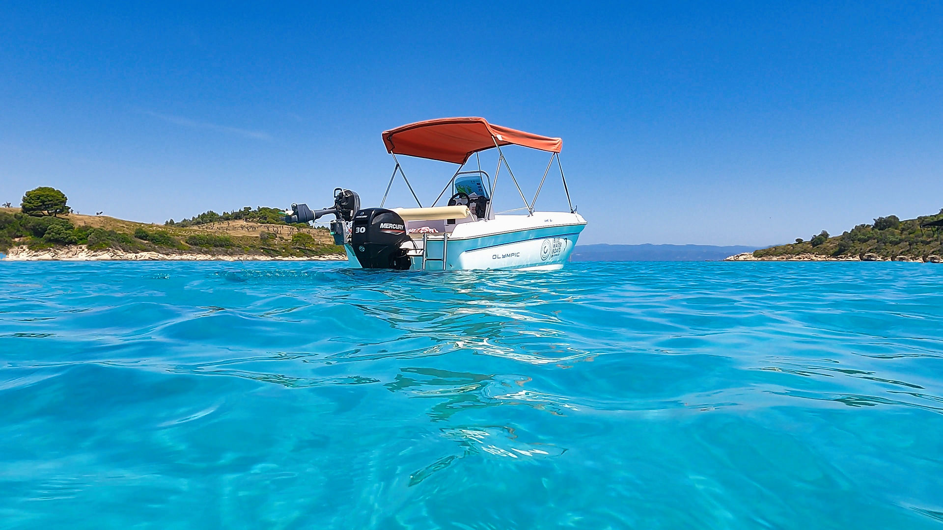 Meer und blauer Himmel, etwas Landschaft von recht und Links, mittig ein Boot mit rotem Dach