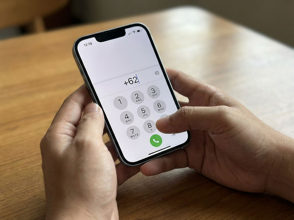 Person dialling +62 on iPhone keypad