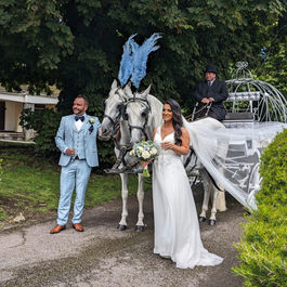 Bride and groom stood with wedding carriage