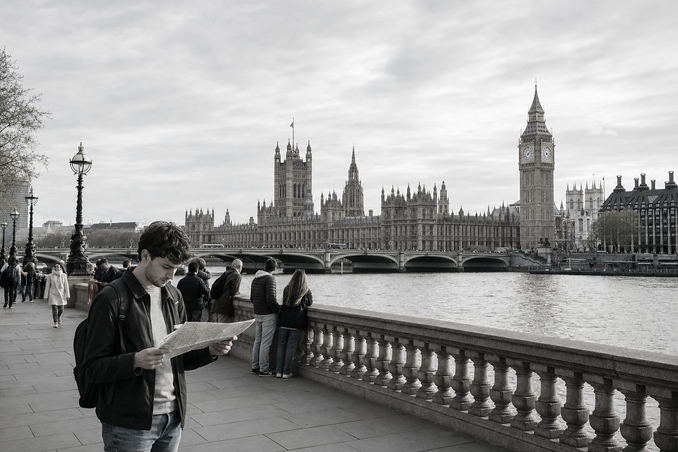 A man holding a map stands by the Thames with the Houses of Parliament and Big Ben in the background.