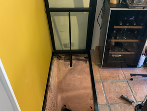 Trappe de sol vitrée en acier, alliant transparence, sécurité et ouverture fluide par vérin hydraulique, avec escalier d’accès au sous-sol.