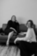 Two smiling women, one on a couch, one on the floor