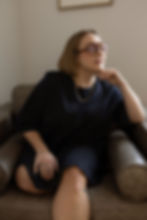 Woman with glasses sitting thoughtfully in armchair