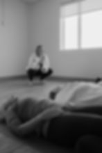 Somatics instructor observes students on floor
