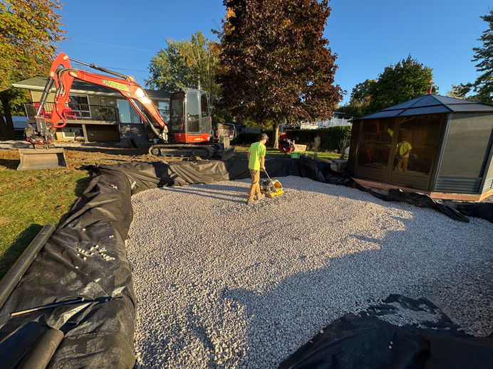 levelling and grading the earth for the construction of interlock patio with natural armour stone stairs, with armour stone retaining wall. 