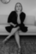 Woman sitting on couch, legs crossed, hand on chin
