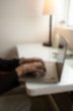 Hands typing on a laptop on a white desk