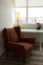 Brown armchair, desk, and lamp by a window