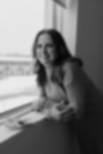 Smiling woman leaning on a windowsill looking out a window