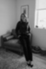 Smiling woman in black and white leaning on a couch