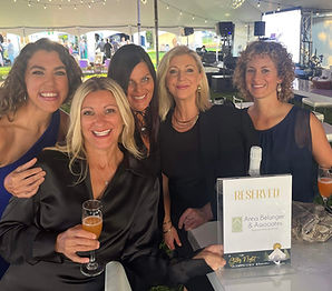 Five women smiling, with a DR SERRETTE sign about Champagne Anna Belanger.