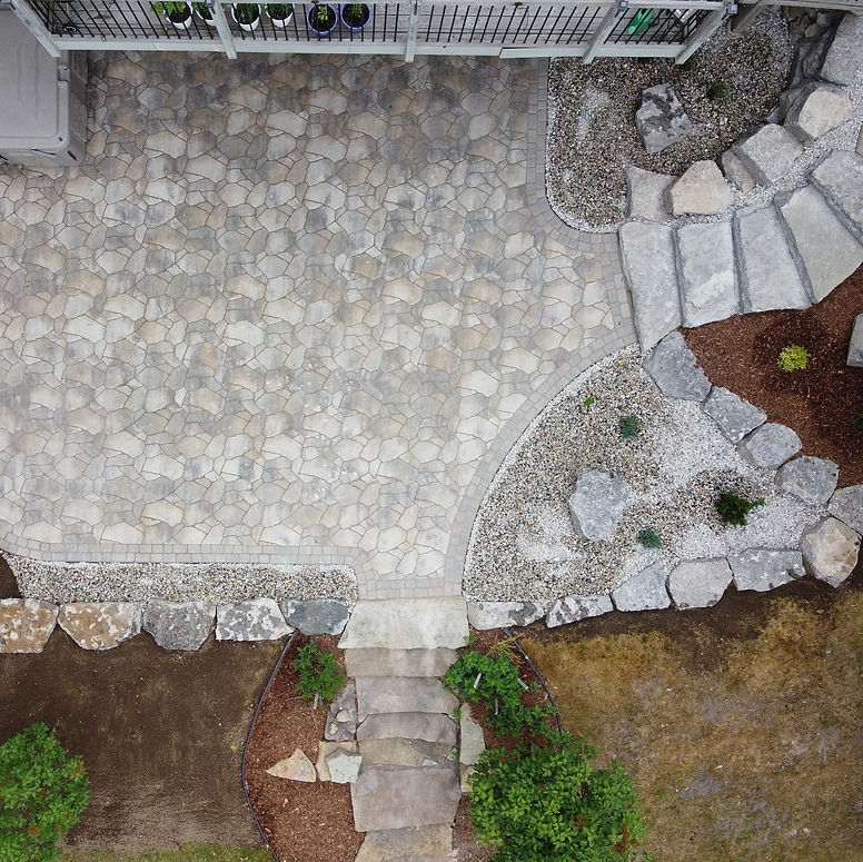 Aerial view of a gray stone patio with stepping stones and landscaping.