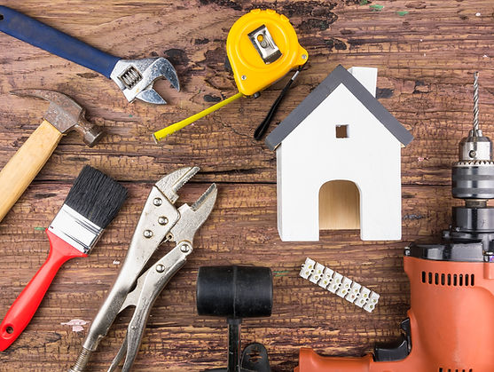 Wooden white house toy and construction tools on wooden background with copy space.Real es