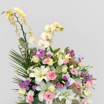 Vazoda çeşitli renklerde çiçekler, beyaz zambaklar, pembe güller, mor çiçekler.