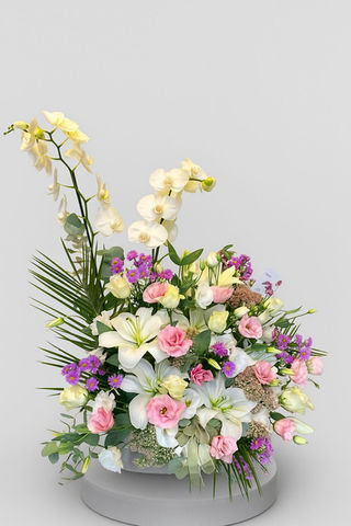 Vazoda çeşitli renklerde çiçekler, beyaz zambaklar, pembe güller, mor çiçekler.