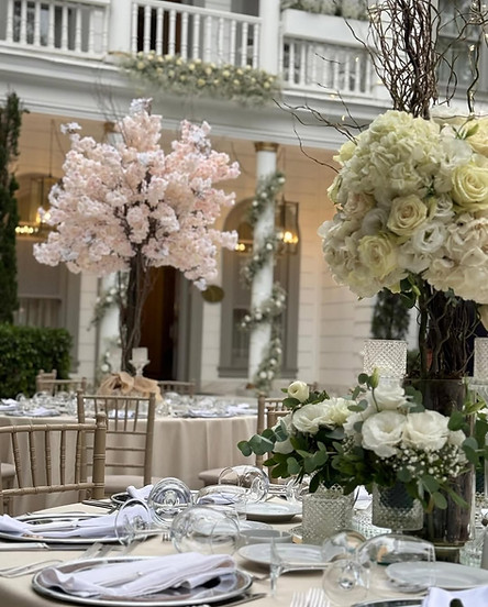 Düğün masası çiçeklerle süslenmiş, beyaz ve pembe çiçekler, zarif bir ortam.