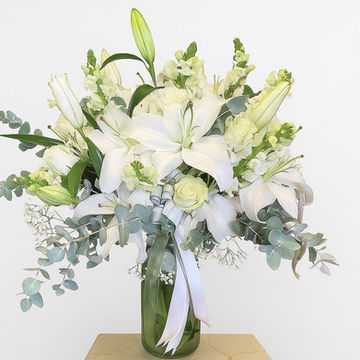 Beyaz zambaklar, yeşillikler ve kurdele çiçek aranjmanı, beyaz arka plan üzerinde.