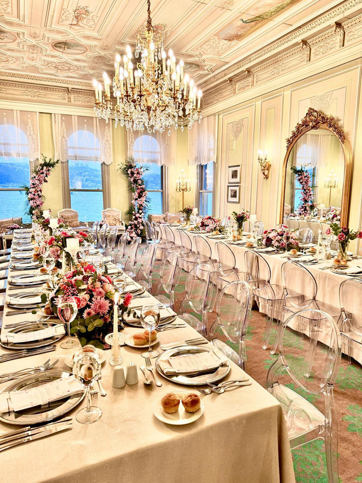 Zarif bir yemek masası çiçekler ve aynalarla süslenmiş, davet düzenlenmiş.