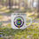 Thumbnail: White mug with The Maggenary logo in forest setting, The Maggenary Enamel Mug.