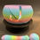 Thumbnail: Colorful rainbow plant pot with the letter J, The Maggenary sticker.