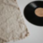 Black vinyl record beside textured cream fabric