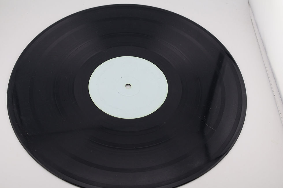 Black vinyl record with a plain white centre label on a light work surface.